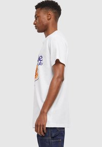 White cotton t-shirt featuring a colorful graphic of a plate of food and text. Short sleeves with rounded neckline, relaxed fit.