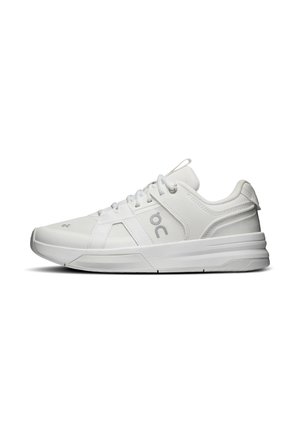 Hvid atletisk sneaker med mesh- og læderpaneler, snørebånd, polstret sål og logo på siden, vist i profil.