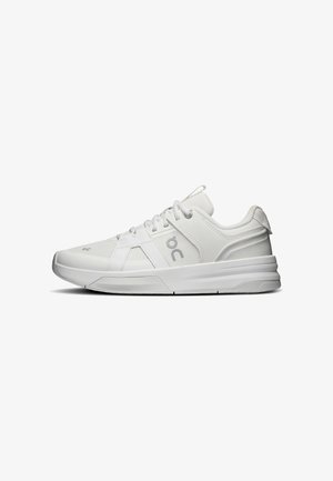 Biały sportowy sneaker z panelami z siateczki i skóry, sznurowany, z amortyzowaną podeszwą i logo po boku, pokazany w widoku bocznym.