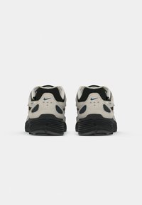 Melnā un baltā pāra Nike P-6000 sporta apavi no aizmugures ar melniem zolem un zilo logotipa detaļām.