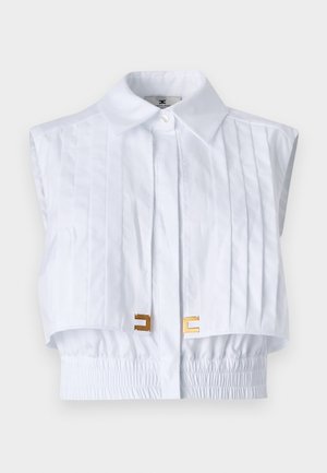 White cropped shirt with a pointed collar, pleated front, elastic waistband, and gold hardware accents. Smooth texture, sleeveless design.