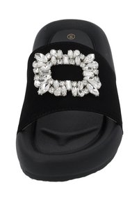 Black slide sandal featuring a wide band adorned with a rhinestone buckle, set on a textured black sole. Smooth fabric and cushioned footbed.