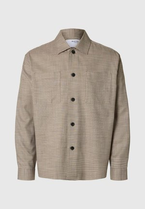 Camicia a scacchi beige con colletto americano, maniche lunghe, chiusura frontale con bottoni e due tasche sul petto. Bottoni neri in evidenza.