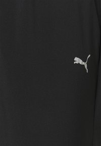 Zwart sportshirt gemaakt van gladde stof met een klein wit Puma-logo op de linkerborst. De textuur lijkt zacht en lichtgewicht.