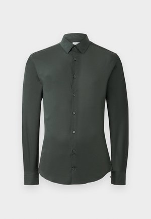 Camisa de manga larga verde oscuro con collar clásico, cierre frontal de botones y textura de tela suave. Presenta puños abotonados y un corte entallado.