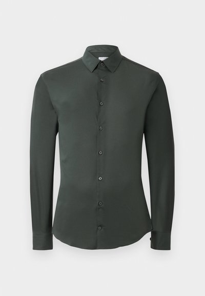 Cămașă lungă cu mânecă închisă la culoare, de un verde închis, cu guler clasic, închidere cu butoni în față și textură fină. Prezintă manșete cu butoni și o croială ajustată.