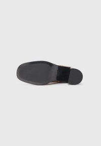 Suola di scarpa nera con una finitura liscia, bordi arrotondati e una leggera lucentezza; progettata per la durata con dettagli minimali nel motivo.