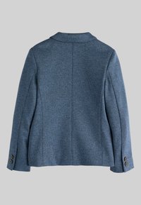 Texturovaná modrá bunda s klopovým límcem, dlouhými rukávy a manžetami na dva knoflíky; má oblečený střih a detail centrálního švu na zadní straně.