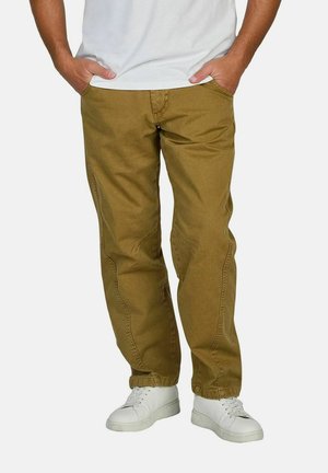 Tan chinos with a relaxed fit, featuring side pockets and visible stitching details, paired with white sneakers.