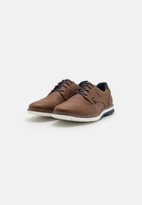 Chaussures en cuir marron avec bout rond, lacets noirs, accents navy et semelle en caoutchouc blanche. Présente des détails de couture le long des bords.