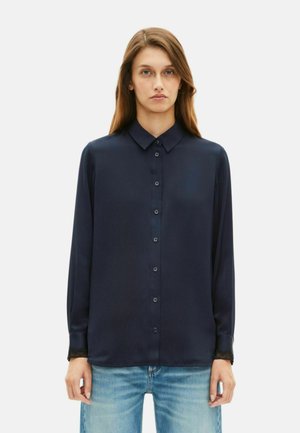 Marineblauwe blouse met lange mouwen van gladde stof, voorzien van een knoopsluiting aan de voorkant, een klassieke kraag en kantaccenten op de manchetten. Gedingd met denim.