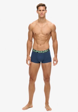 Marineblå bomulds boxer briefs med en sort linning, der har en lys grøn 'SUPERDRY'-logo. Glat tekstur, tætsiddende design, længde til midt på låret.