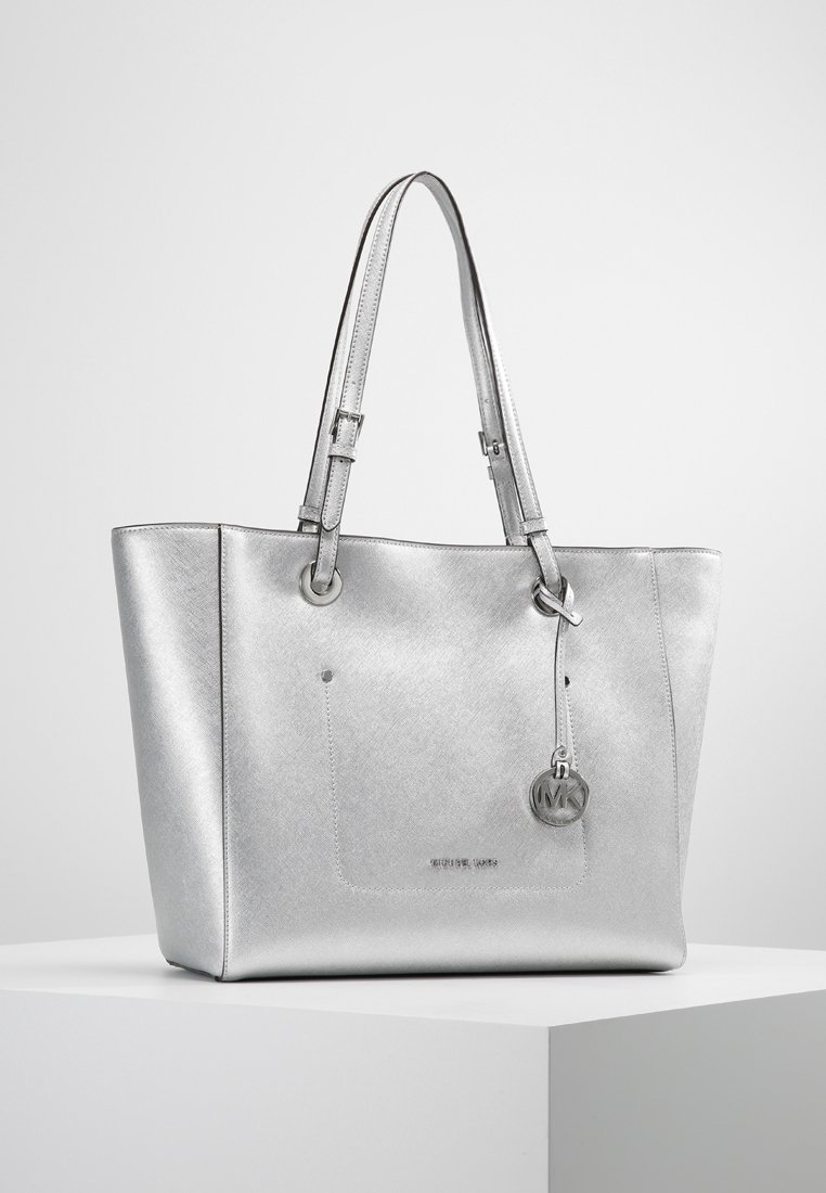 Srebrna torba na ramię wykonana z teksturowanego materiału, z podwójnymi uchwytami, zewnętrzną kieszenią i okrągłym charms'em z logo.
