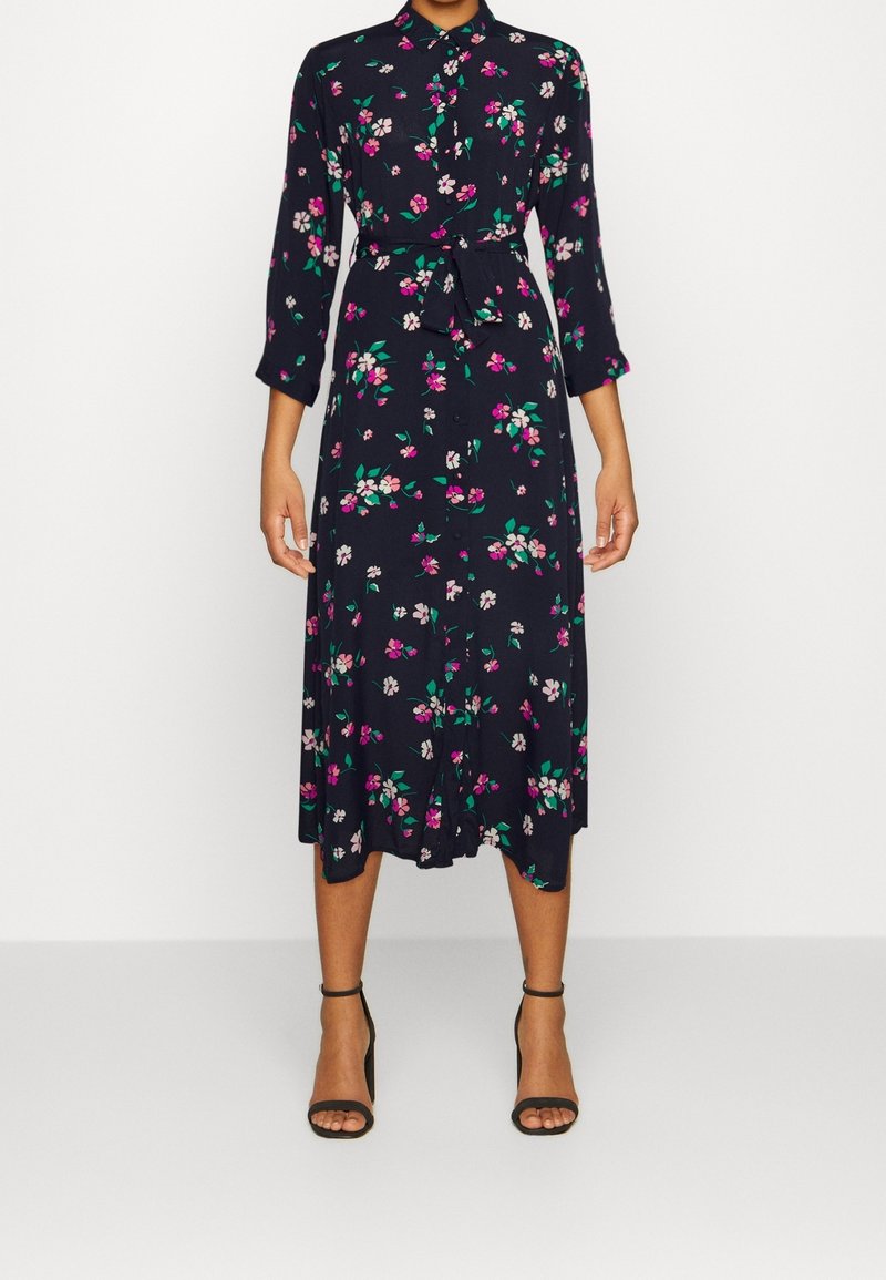Květinové šaty s námořnickým pozadím, zdobené růžovými a zelenými květy, s knoflíkovou přední částí, tříčtvrtinovými rukávy a páskem v pase.