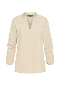 Maglietta beige a maniche lunghe con scollatura a V, polsini arricciati e una texture morbida. Design semplice, senza motivi o decorazioni visibili.