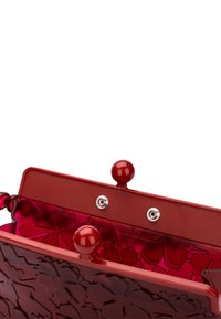 Rote Kunststofftasche mit einem strukturierten Blumenmuster. Verfügt über einen Klippverschluss und zwei abgerundete Obergriffe. Das Innere ist glatt und glänzend.