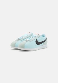 Sneaker azzurri chiari con un logo swoosh nero, dettagli in suede, lacci rotondi e suola in gomma testurizzata per una buona presa e durata.