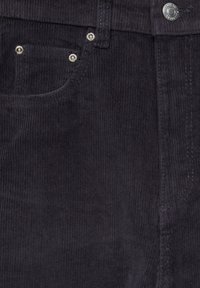 Pantalon en velours côtelé gris foncé avec des côtes verticales. Il est doté d'une poche avant, de quincaillerie argentée et de détails de couture visibles.