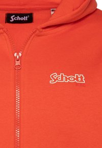 Felpa rossa con zip e texture a costine, dotata di zip frontale e logo ricamato bianco nella parte sinistra del petto.