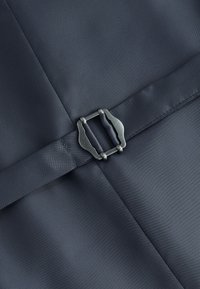 Dark fabric with stitched seams and a black textured belt secured by a matte black metal buckle centered on the material.