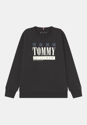Czarna bluza z okrągłym dekoltem, z dużym napisem "TOMMY HILFIGER" i czterema wzorzystymi kwadratami w kolorze niebieskim. Mankiety i dół bluzy wykończone ściągaczem.