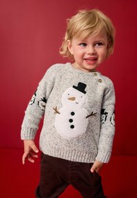 Pull en tricot gris avec une appliqué de bonhomme de neige fluffy blanc et des boutons noirs, accentué par des motifs de bonhomme de neige noirs sur les manches.