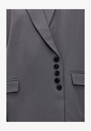 Grijze blazer met een gladde textuur, voorzien van een notch-revers, zes zwarte knopen en twee zijzakken. Getailleerde pasvorm met een gestructureerde vorm.