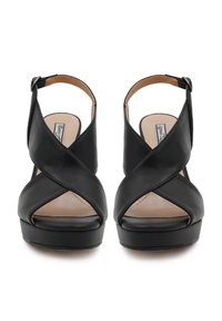 Sandali platform in pelle nera con design incrociato, punta aperta e cinturino alla caviglia. Superficie liscia e soletta imbottita per il comfort.