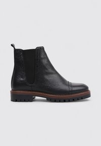 Black leather Chelsea boots with a textured upper, elastic side panels, and ribbed sole. Low heel with decorative stitching detail.