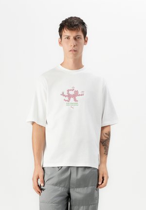 Hvit bomull t-skjorte med rund hals og korte ermer. Har et rosa grafisk design med tekst i grønt og rosa i midten.
