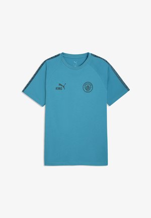 Blå kortærmet sportstrøje med sort Puma-logo og "KING" tekst på højre bryst samt Manchester City-mærke på venstre bryst.
