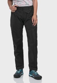 Schwarze wasserdichte Hose mit elastischem Bund und vorderem Reißverschluss. Glatte Textur, lockere Passform mit geraden Beinen. Mit einem Logo akzentuiert.