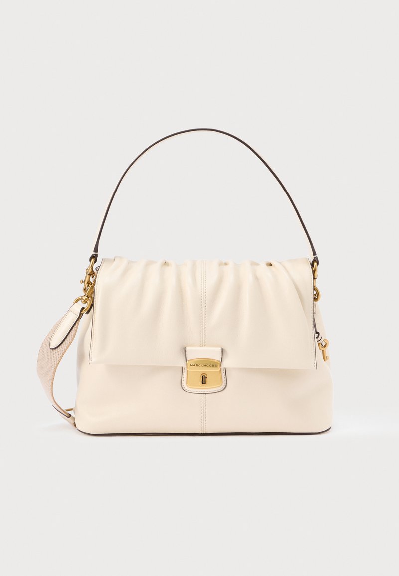 Cremefarvet læderhåndtaske med en opsamlet top, guldfarvet hardware og aftagelig rem. Har en klaplukning og kontrasterende brunt håndtag.