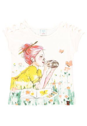 Fille aux cheveux roses en chemise jaune tient un appareil photo allongée dans l'herbe avec des fleurs, des papillons et un carnet de croquis ouvert avec une palette de peinture.