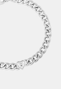 Bracciale in metallo argentato con catena a grandi anelli e un ciondolo a forma di cuore con un accento in pietra trasparente. Texture liscia, finitura lucida.