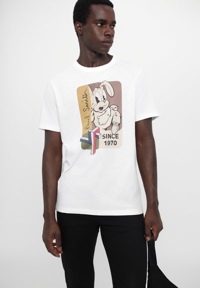 Balta kokvilnas T-krekls ar mulsīnām krāsām kartona zaķa grafiku un tekstu "Paul Smith" un "SINCE 1970". Īsas piedurknes, apaļa dekoltē.