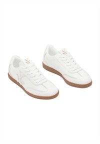 Baskets en cuir blanc avec une semelle en caoutchouc beige, arborant un logo discret, un laçage à fermeture et des accents cousus sur les côtés.