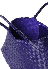 Bolso tote de cuero tejido color púrpura intenso con asas trenzadas y una parte superior abierta que muestra una pequeña etiqueta interior.