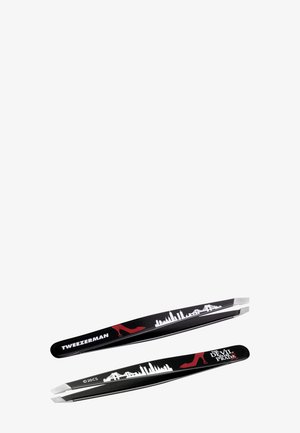 Pincettes Tweezerman noires avec silhouette de ville blanche, motif de talon haut rouge et marquage "The Devil Wears Prada" sur les manches.