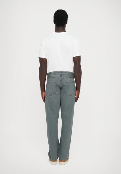 Grå denimjeans med en rak bendesign, som har två bakfickor och en kontrasterande midja. Bärs med en enkel vit t-shirt med kort ärm.