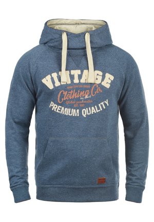 Sudadera azul con bolsillo frontal, que presenta un diseño vintage. Tiene una capucha forrada en color crema y cordones, con texto impreso en colores contrastantes.