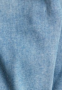 Tela de mezclilla azul claro con una textura suave, que presenta un patrón granuloso y ligeras variaciones de color, creando una apariencia clásica de mezclilla.