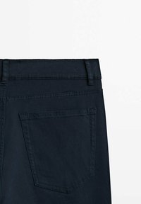 Vue arrière d'un pantalon en denim noir montrant la taille avec passants de ceinture et une seule poche arrière sur fond blanc.