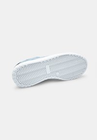 Baskets bleues avec une surface texturée, semelle en caoutchouc blanc présentant un motif en zigzag et un talon plat. Détail de marque minimal.