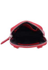 Bolso rojo con cremallera, con un exterior suave, herrajes plateados y un forro negro suave. El interior es espacioso sin compartimentos visibles.