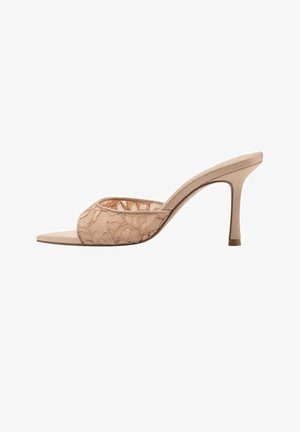 Mula beige destalonada con tira de encaje y tacón alto y delgado, mostrada de lado sobre fondo blanco.