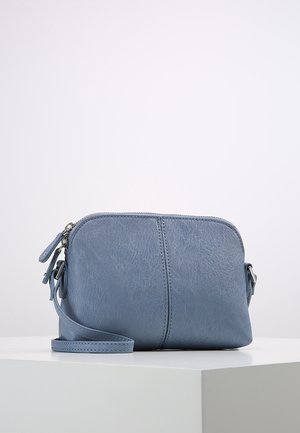 Small blue leather crossbody bag with zipper closure and adjustable strap, resting on a white pedestal against a plain background.