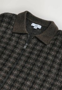 Strukturierte braune Wollmischung mit Reißverschlussjacke und dunklem Kragen, mit einem Hahnentrittmuster und silbernen Metallreißverschlussdetails.