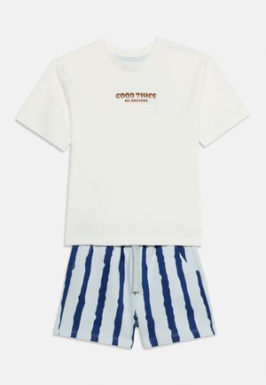 Camiseta blanca de manga corta con el texto "GOOD TIMES ALL DAY LONG" combinada con pantalones cortos azul claro con rayas verticales azul oscuro.