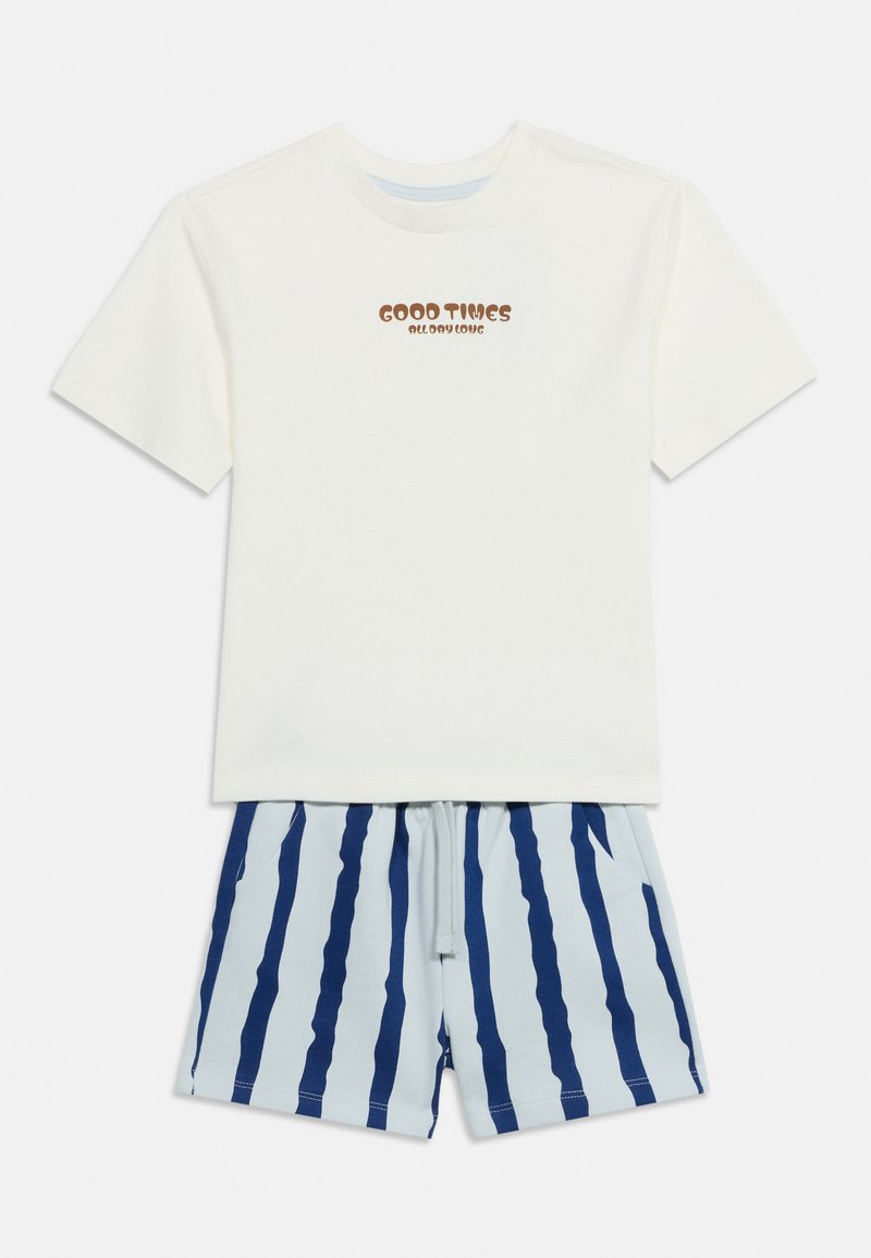 Λευκό κοντομάνικο T-shirt με το κείμενο "GOOD TIMES ALL DAY LONG" συνδυασμένο με ανοιχτό μπλε σορτς με κατακόρυφες σκούρες μπλε ρίγες.